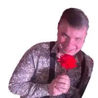 a man in a paisley shirt is smiling while holding a red rose