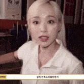 a woman with blonde hair and a white shirt with the word hyeon on the bottom