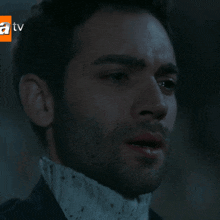 a close up of a man 's face with a tv advertisement behind him