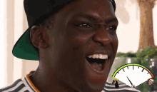 a man wearing a hat and a striped shirt is smiling with a speedometer in the background