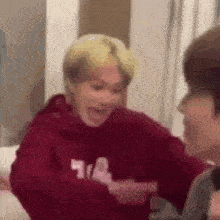 a man in a red hoodie is talking to another man in a red hoodie .