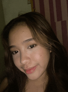 a close up of a girl 's face with a striped wall behind her