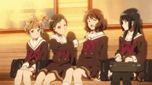 a group of girls are sitting on a bench and one of them has a briefcase on her lap