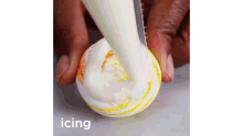 a person is icing a marshmallow with a piping bag and a knife .