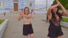 two women are dancing in front of a building