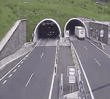 two cars are driving through a tunnel on a highway .