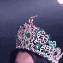 a woman is wearing a crown with green stones on it