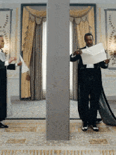a man in a tuxedo holds a piece of paper in his hand