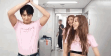 a man in a pink shirt is standing next to two women in pink shirts .