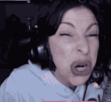 a woman wearing headphones making a funny face with her eyes closed
