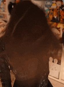 a woman wearing a black sweater and a black dress is standing in front of a shelf filled with stuffed animals .
