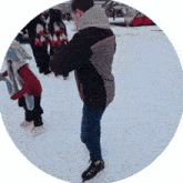 a man in a black and brown jacket is standing on a snowy ice rink