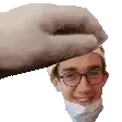 a hand is holding a man 's head with glasses and a mask on it .