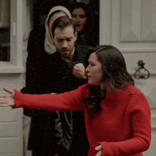 a woman in a red sweater is standing next to a man in a black coat
