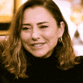 a woman wearing hoop earrings smiles for the camera
