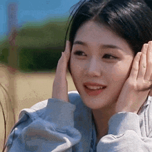a woman covering her ears with her hands and smiling .