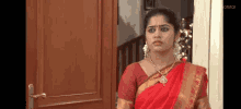 a woman in a red sari is standing in a doorway .