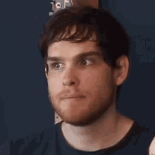 a man with a beard is wearing a black shirt and looking at the camera