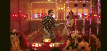 a man and a woman are dancing in a room filled with flowers and lights .