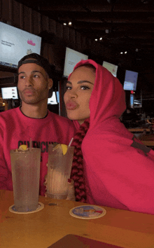 a man and a woman are sitting at a table with a drink and a coaster that says ' duck ' on it