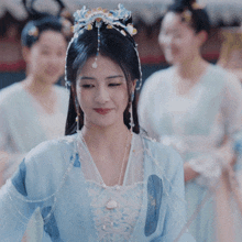 a woman in a blue dress with pearls and flowers on her hair