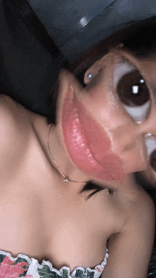 a woman wearing a necklace and a floral top takes a selfie with her mouth open