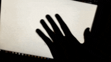 a shadow of a person 's hand is cast on a computer screen