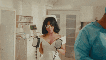 a woman in a nurse 's outfit holds a pair of defibrillators