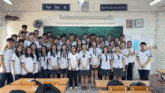 a group of students are posing for a picture in a classroom with a sign above them that says " chiên thiên mỹ "