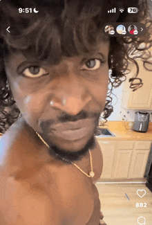 a shirtless man with curly hair looks at the camera with the time 9:51 on his phone
