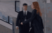 a man in a suit and tie shakes hands with a woman with red hair