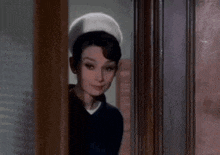 a woman wearing a nurse 's hat is standing in a doorway .