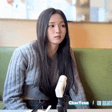 a woman in a grey sweater is sitting at a table with a camera in front of her ..