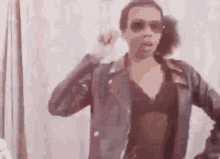 a woman wearing sunglasses and a leather jacket is dancing .