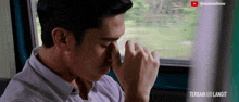 a man covering his eyes with his hands in front of a screen that says ' terbaik ke langit '
