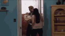 a man and woman are holding a baby in a room .