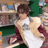 a man wearing a t-shirt that says ' cowboy bona ' is sitting at a counter in a store