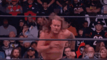 a wrestler is jumping over another wrestler in a wrestling ring in front of a crowd .