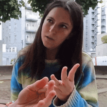 a woman in a blue and yellow sweater is talking to another person