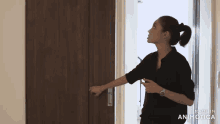 a woman stands in front of a door that says made in animotica on it