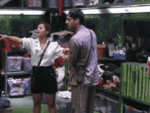 a man and a woman are standing next to each other in a room filled with boxes .