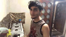 a young man standing in front of a gas stove wearing a tank top with a skull on it