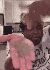 a man in a white shirt is holding something in his hands in a kitchen .