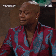 a man with his eyes closed is wearing a red and blue jacket with a hulu logo behind him