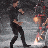a man in a black shirt and black pants is pointing at a red and black superhero