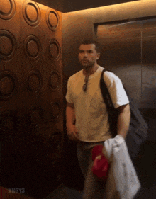 a man in an elevator with kh313 written on the bottom right