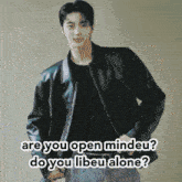 a man in a black leather jacket is standing in front of a wall with the words are you open mindeu