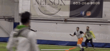 a nelson real estate banner hangs on a wall above a soccer field