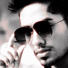 a close up of a man wearing sunglasses with his hand on his face