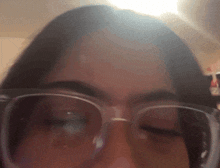 a woman wearing glasses is looking at the camera with her eyes closed